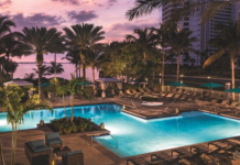 a pool with palm trees and a building in the background