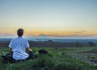 a man sitting on grass looking at the sunset