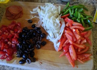 a cutting board with vegetables and pepperoni on it