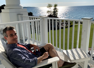 a man sitting on a chair on a porch overlooking a body of water