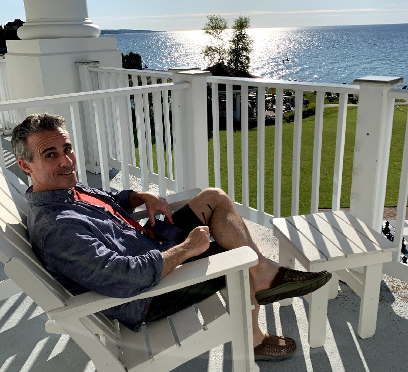 a man sitting on a chair on a porch overlooking a body of water