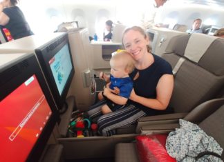 a woman holding a baby in a seat on an airplane