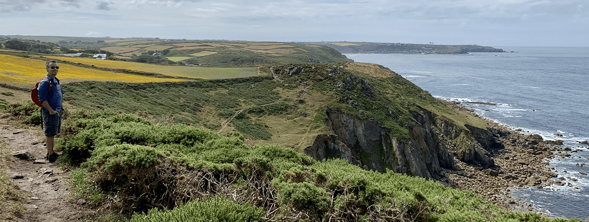 a green hills with a cliff and a body of water