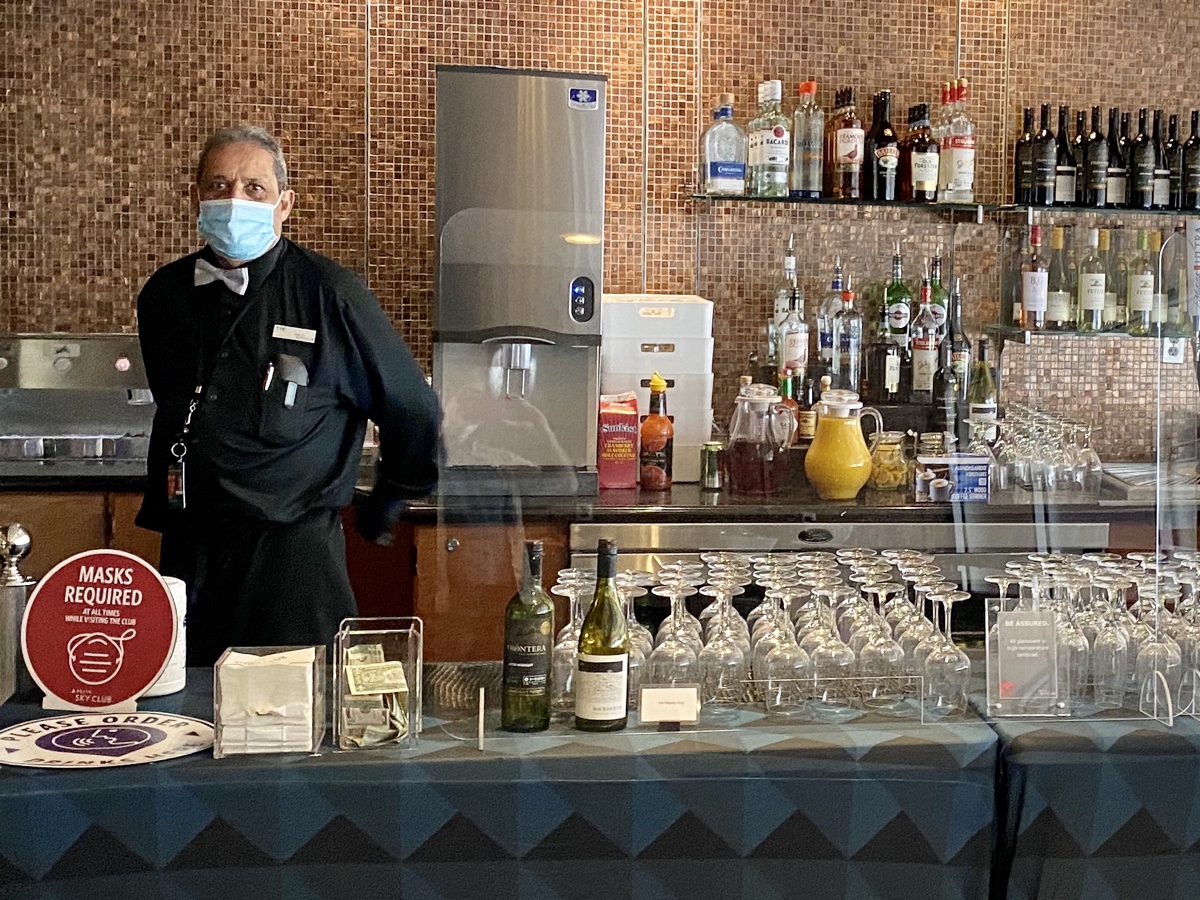 a man wearing a face mask standing in front of a bar