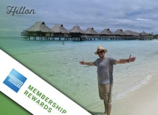 a man standing on a beach with a hut on the water