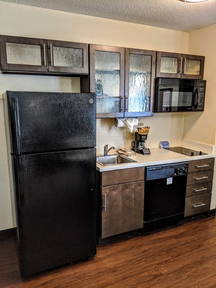 a kitchen with a black refrigerator and a wood floor