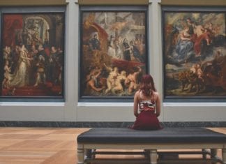 a woman sitting on a bench looking at paintings