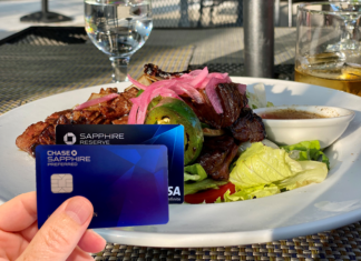 a hand holding a credit card next to a plate of food