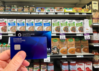 a hand holding a credit card in front of a shelf of food