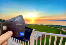 a hand holding two cards on a balcony overlooking a golf course