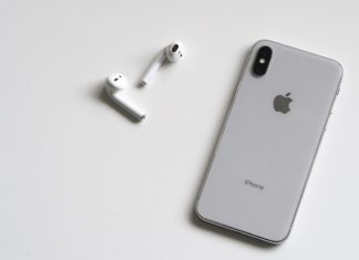 a cell phone and earbuds on a white surface