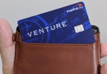 a hand holding a brown wallet with a blue credit card inside