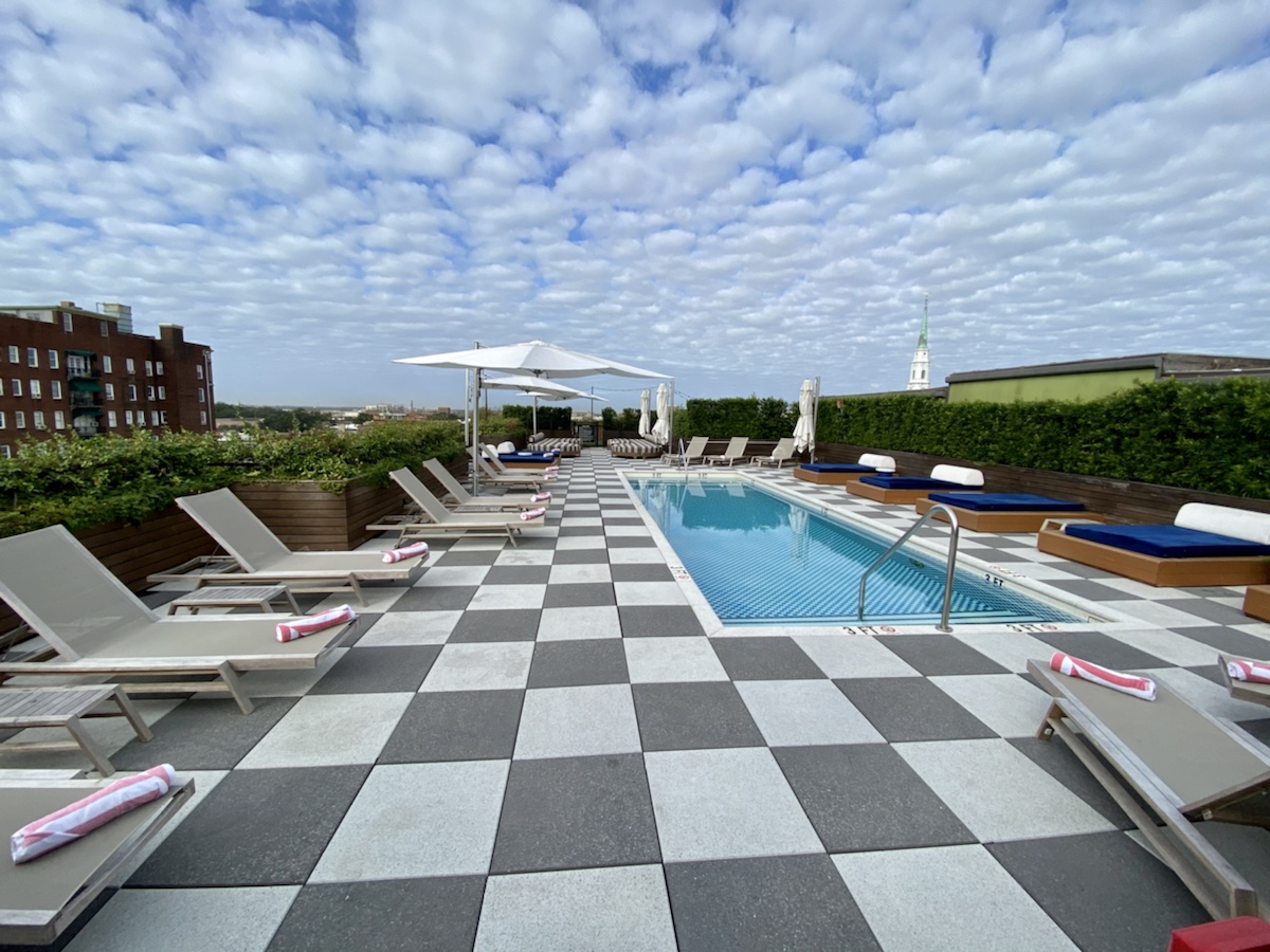 a pool with lounge chairs and umbrellas on a rooftop