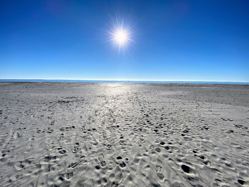 a sandy beach with the sun in the background