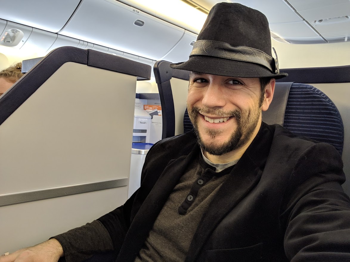 a man wearing a hat and sitting in an airplane