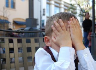 a child covering his face with hands