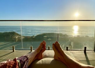 a person's feet on a couch overlooking the ocean