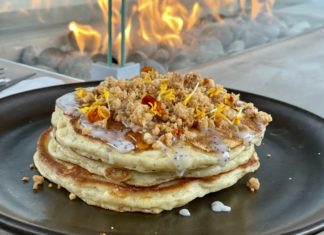 a stack of pancakes with toppings on a black plate