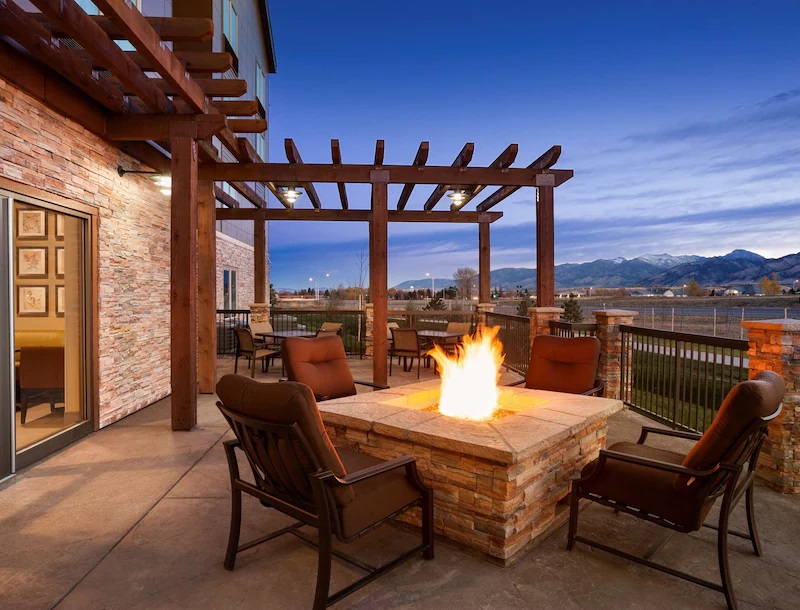 a fire pit with chairs and a pergola
