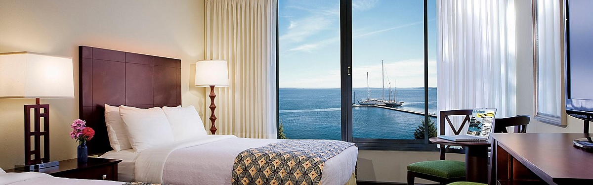a bed with a lamp and a window overlooking the ocean