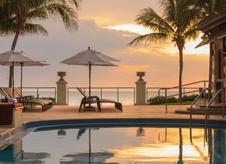 a pool with umbrellas and chairs by a beach