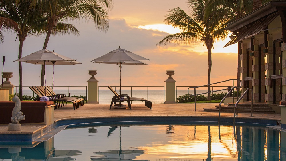 a pool with umbrellas and chairs by a beach