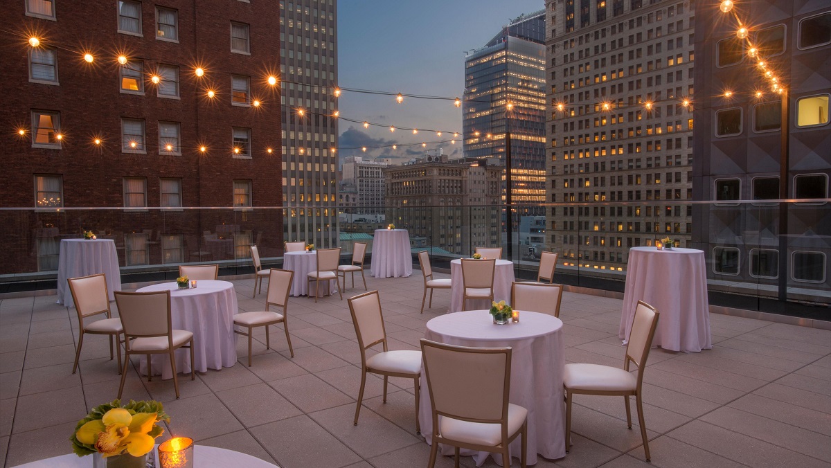 a rooftop patio with tables and chairs and a city skyline