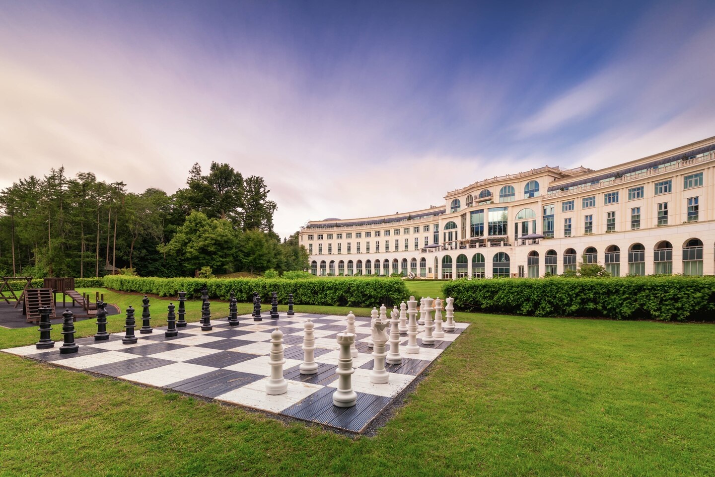 a large chess board in a grassy area with a large building in the background