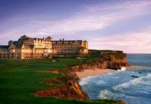 a large building on a cliff overlooking the ocean with Bamburgh Castle in the background