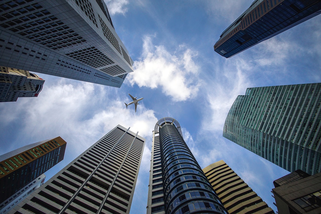 a plane flying in the sky above tall buildings
