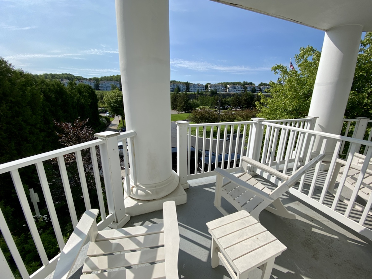 a white porch with a white column and chairs