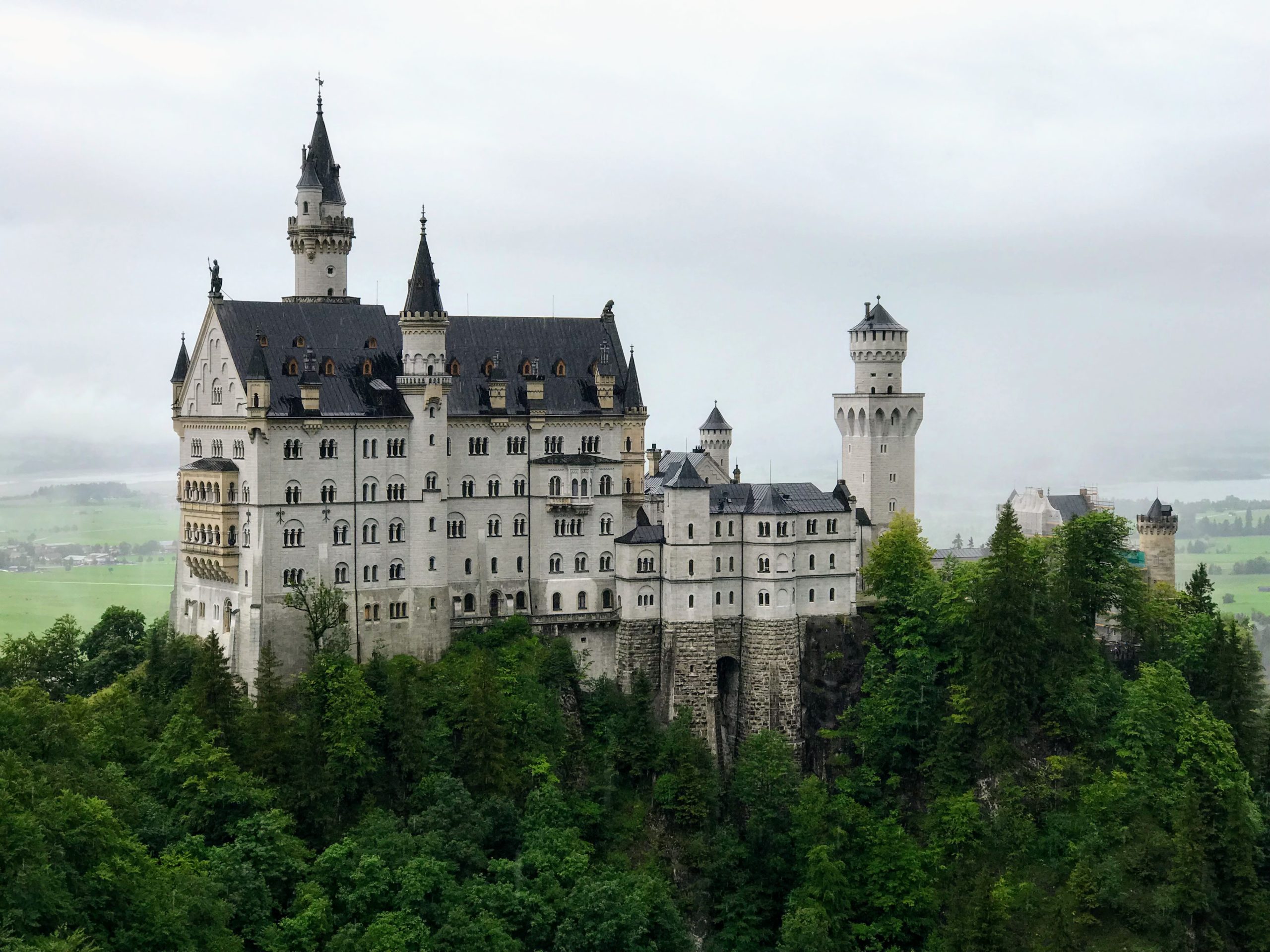 a castle on a hill with Neuschwanstein Castle in the background