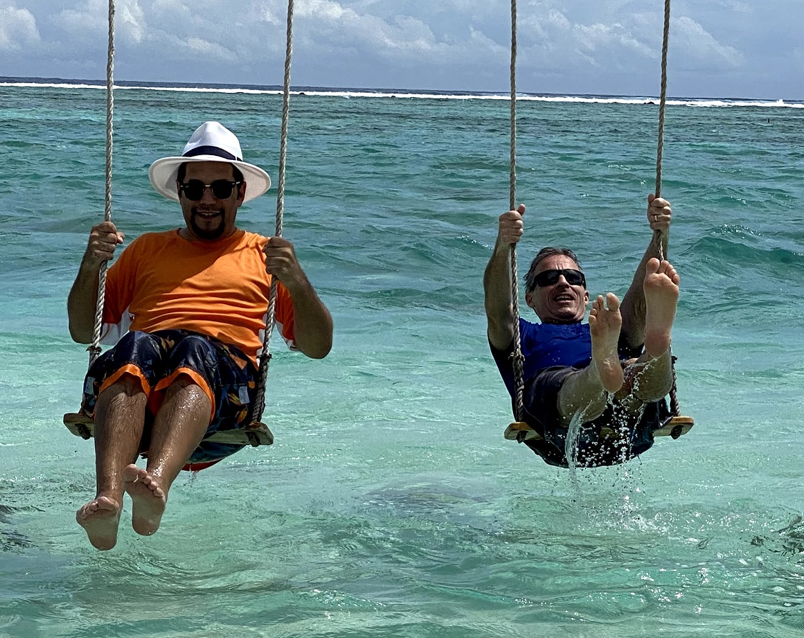 two men swinging on a swing in the ocean