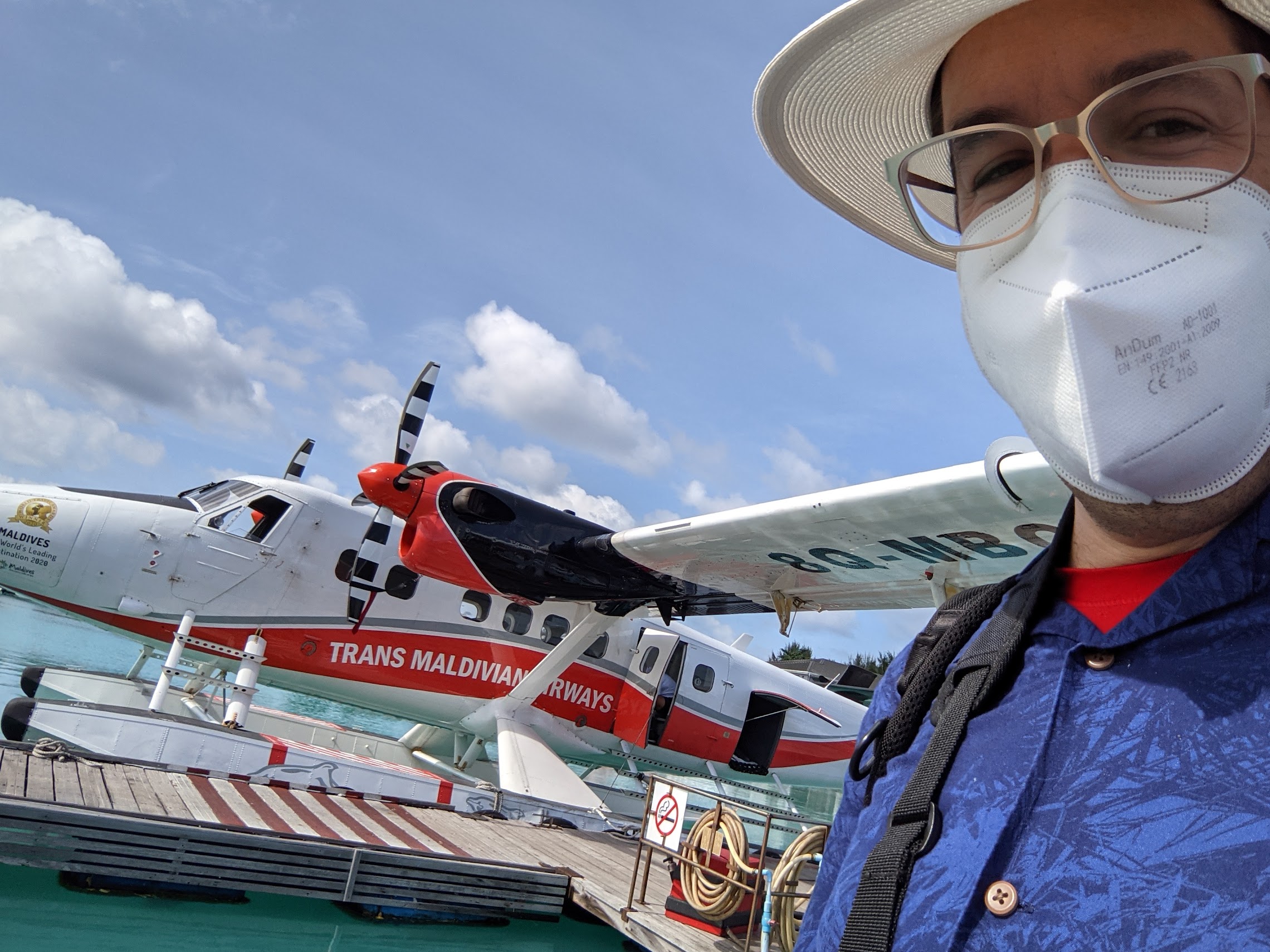 a person wearing a face mask and glasses standing next to an airplane