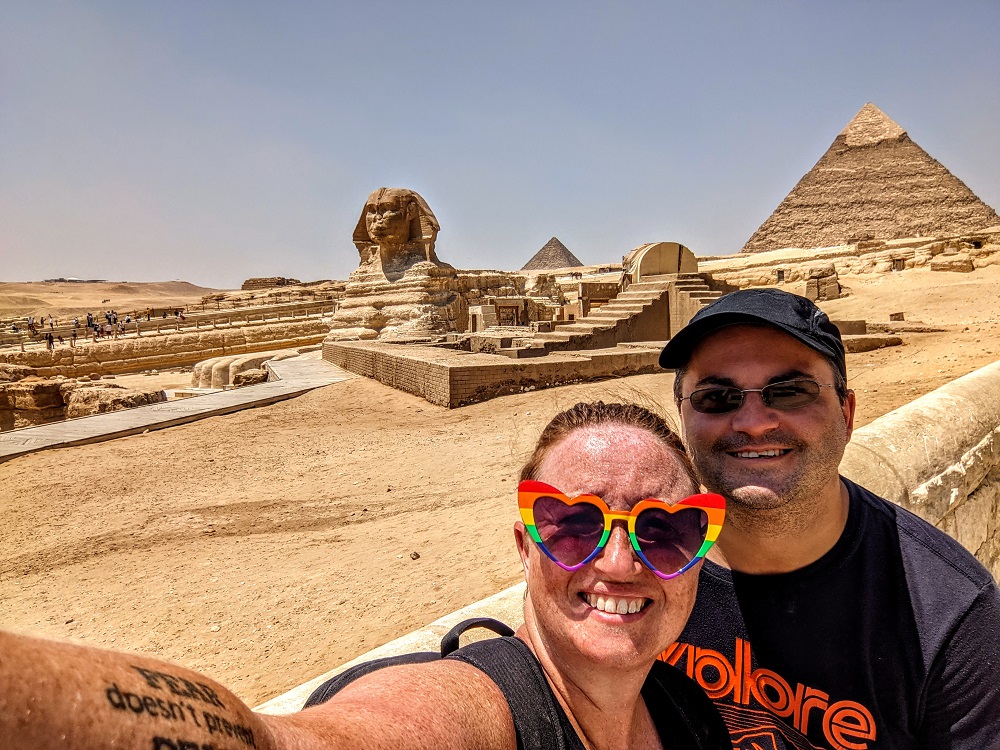 a man and woman taking a selfie in front of a pyramid