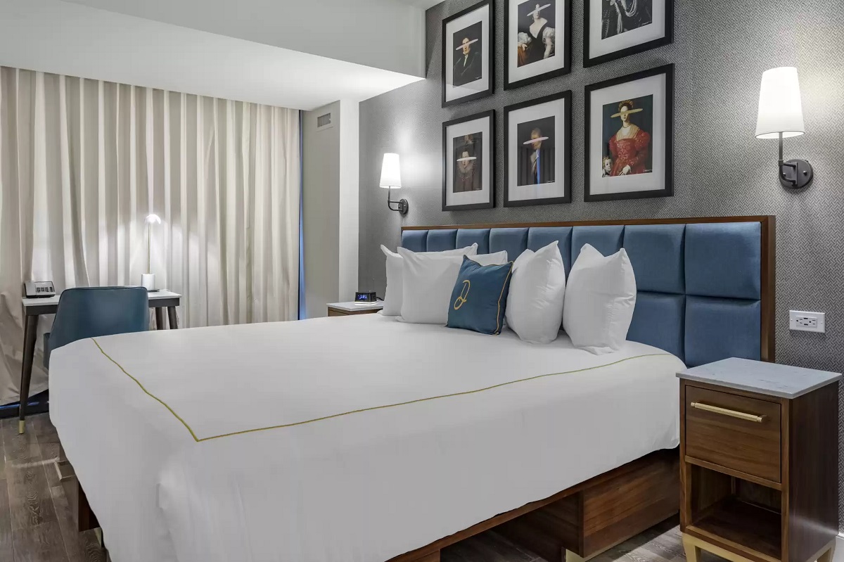 a bed with white sheets and blue headboard in a room