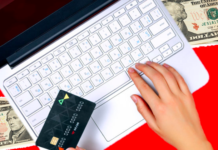 a hand holding a credit card and typing on a laptop