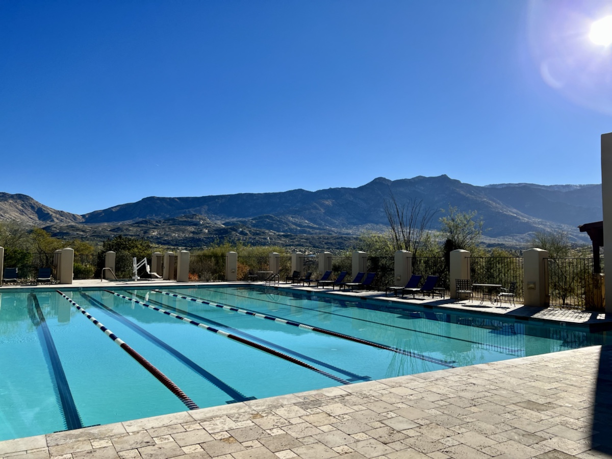 a swimming pool with chairs and a mountain in the background