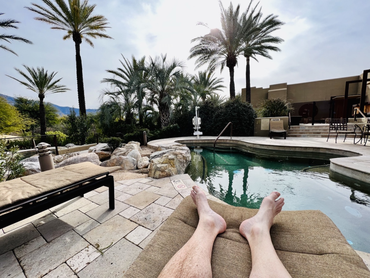 a person's feet on a lounger next to a pool