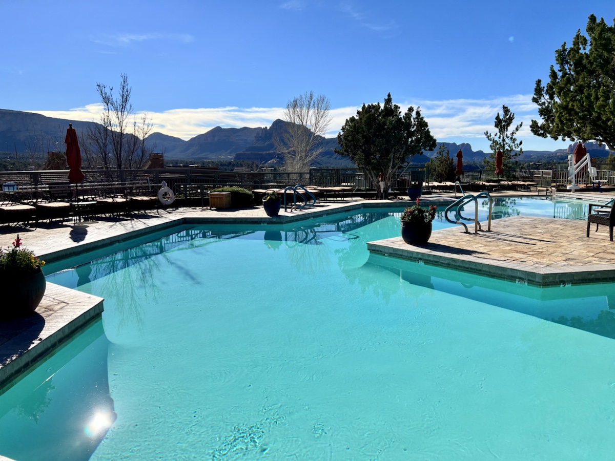 a swimming pool with a deck and trees and mountains in the background