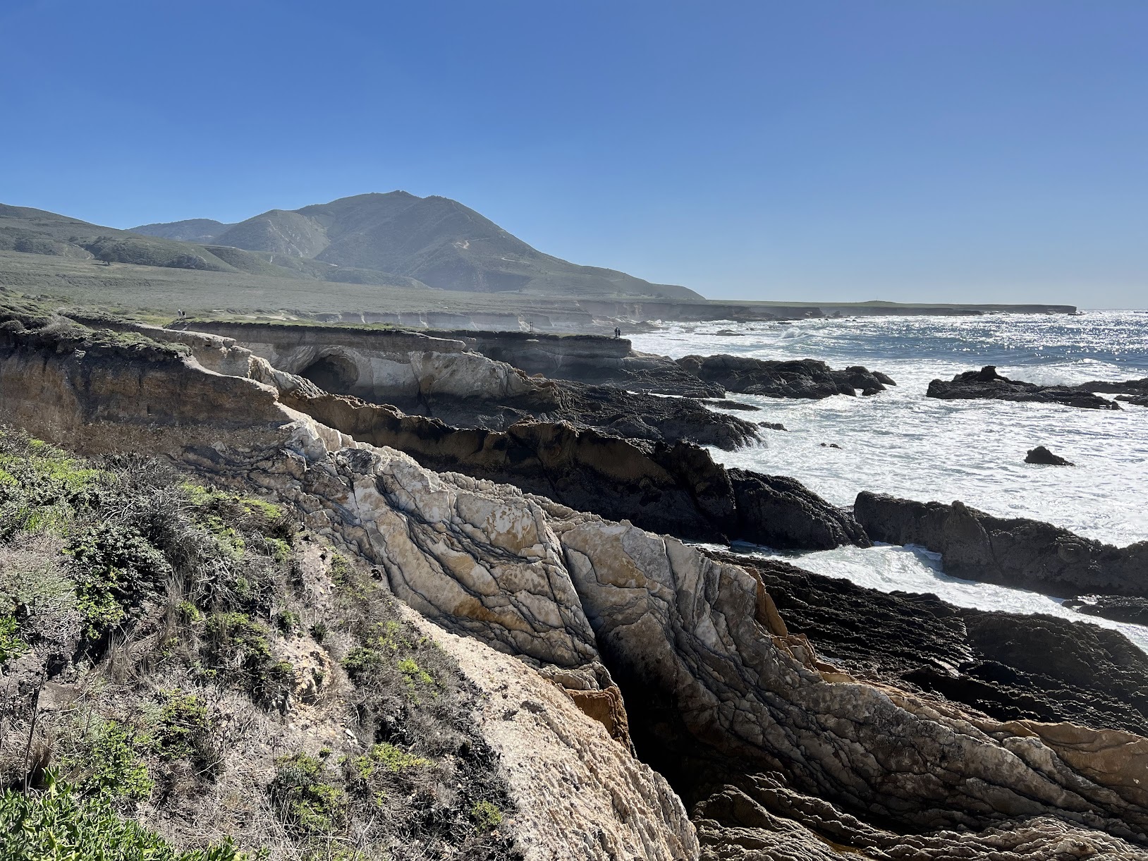 a rocky coastline with water and mountains in the background
