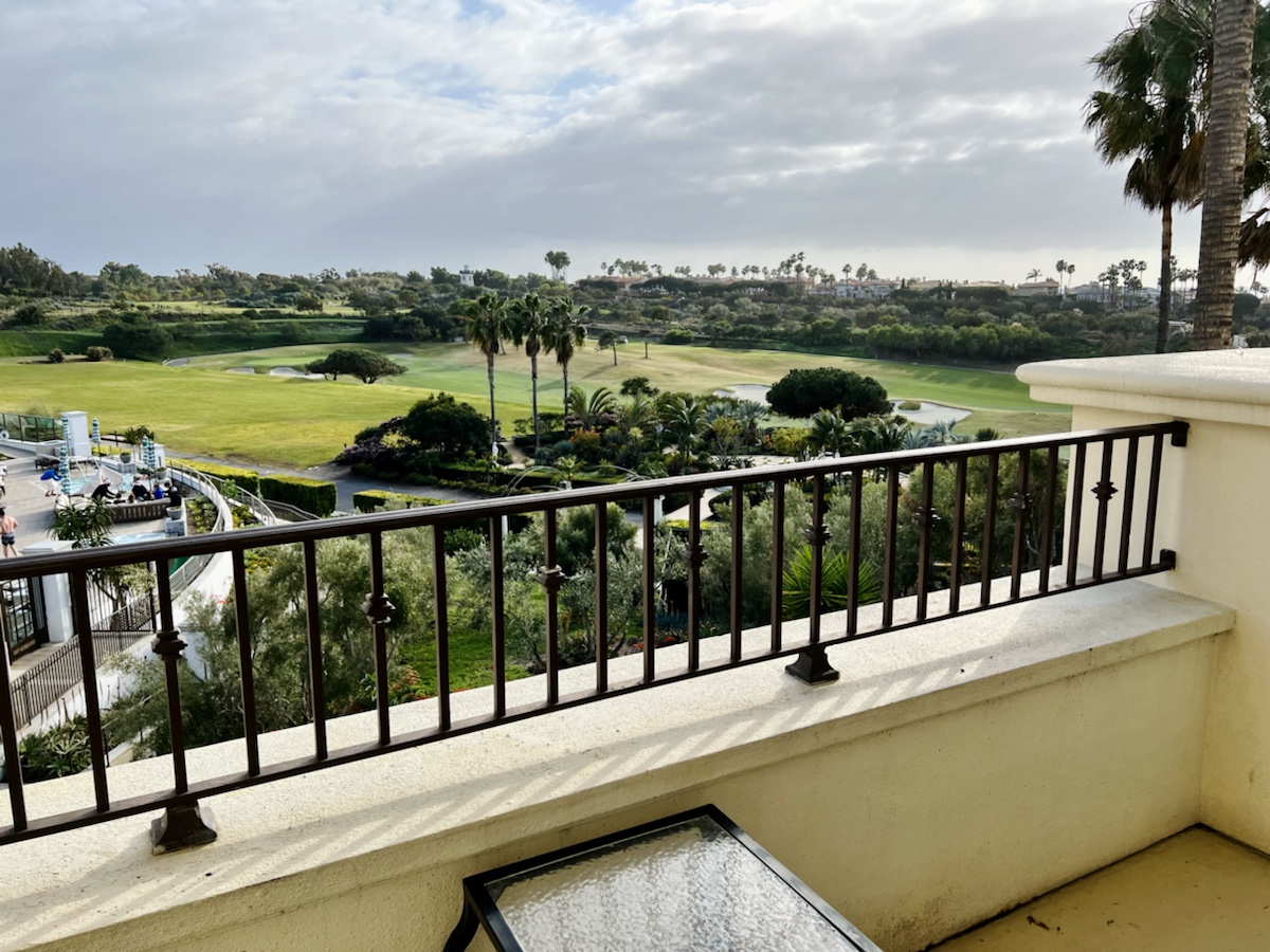 a balcony with a view of a golf course and trees