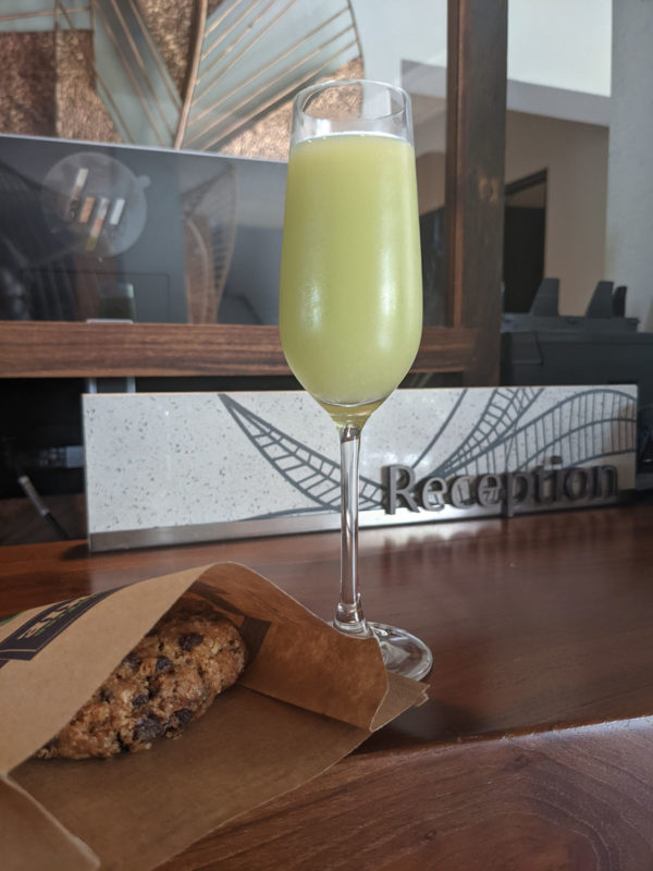 a glass of yellow liquid next to a cookie