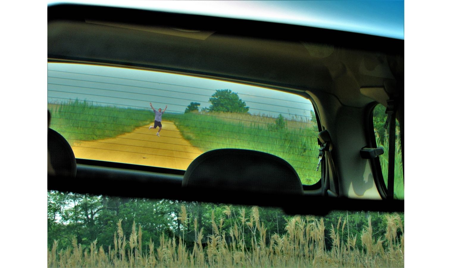 a person running on a dirt road through a car window