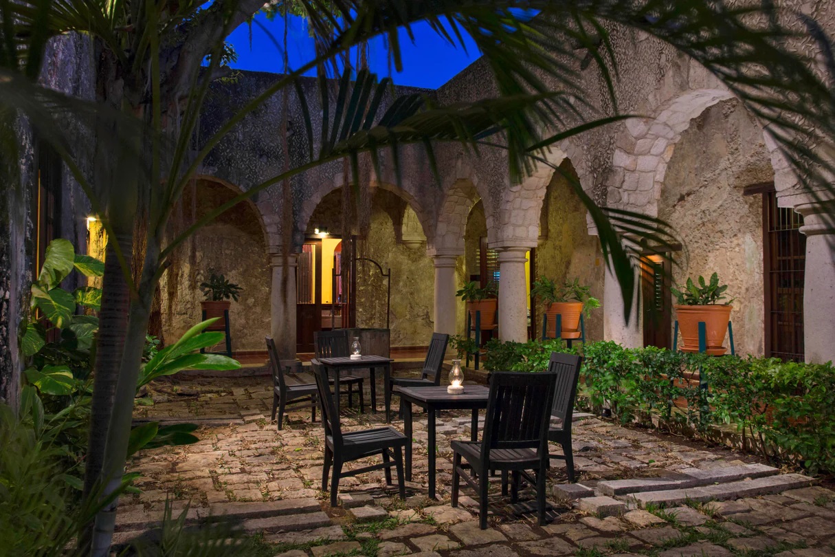 a patio with chairs and tables in the middle of a stone building
