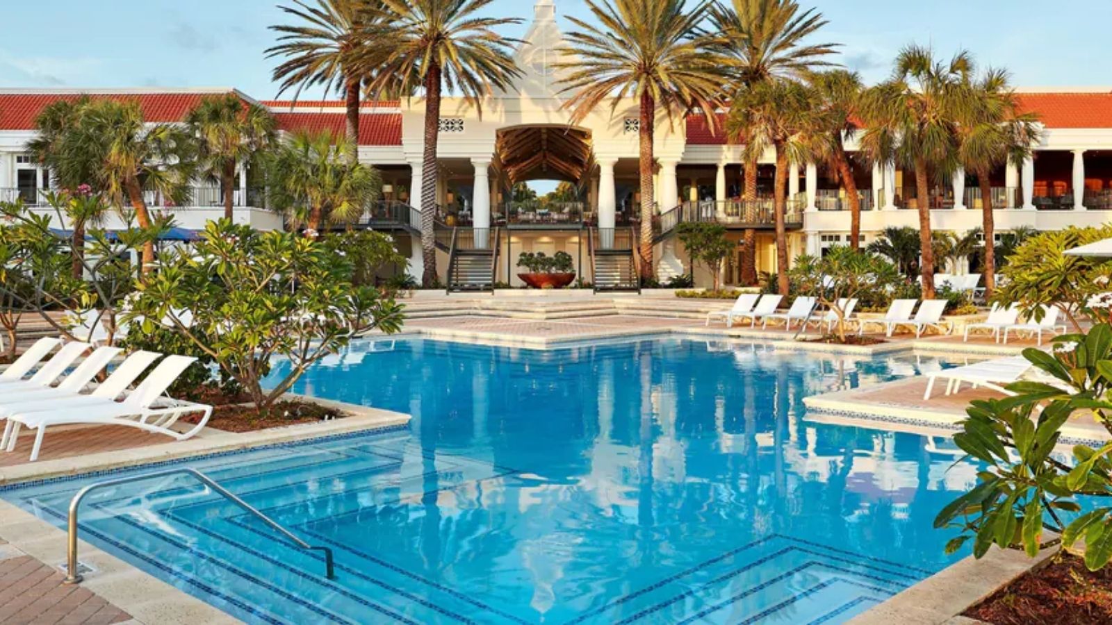 a swimming pool with palm trees and a building