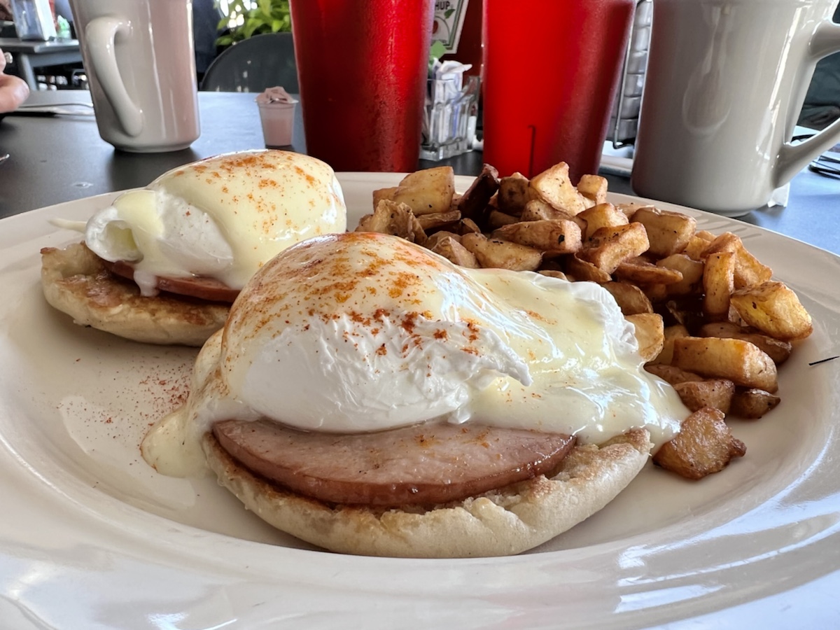 a plate of food with eggs benedict and fries