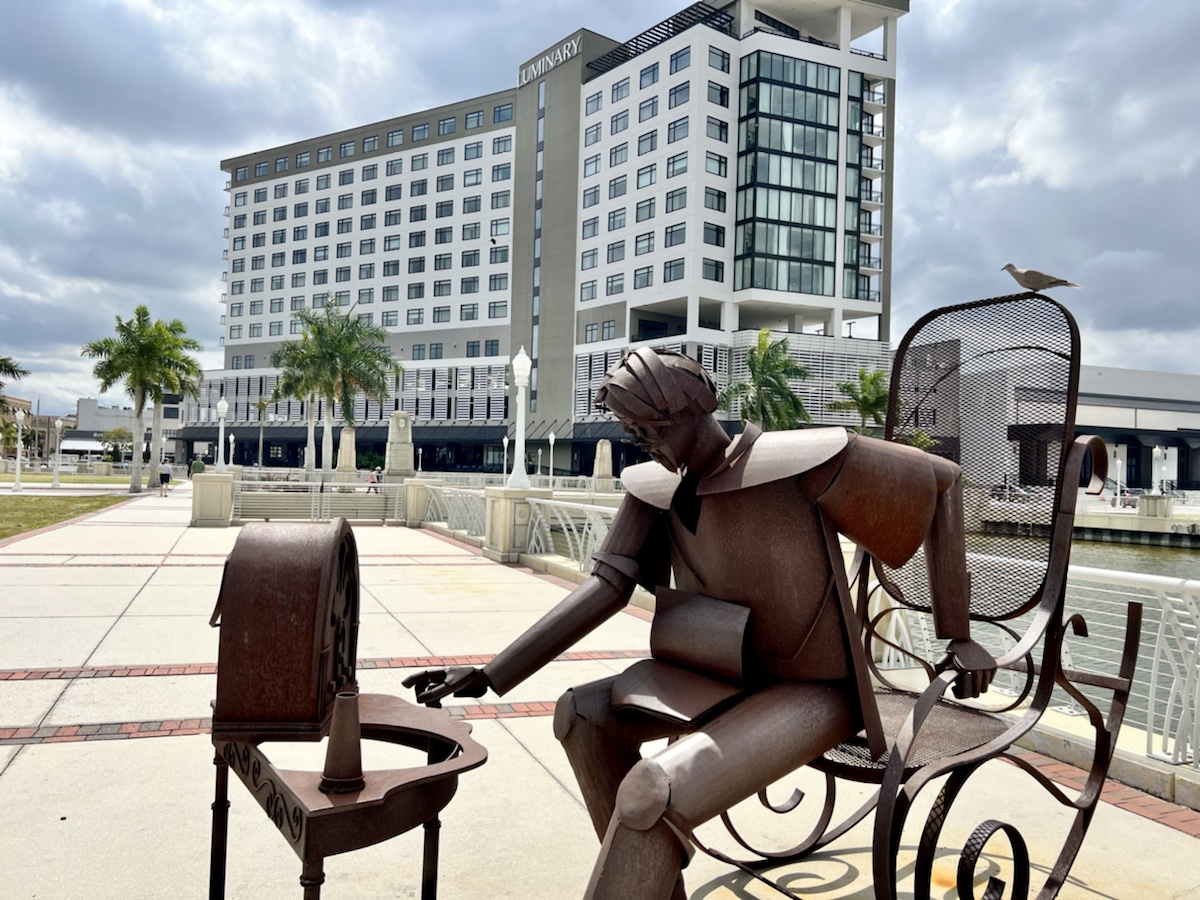 a statue of a man sitting on a bench outside a building