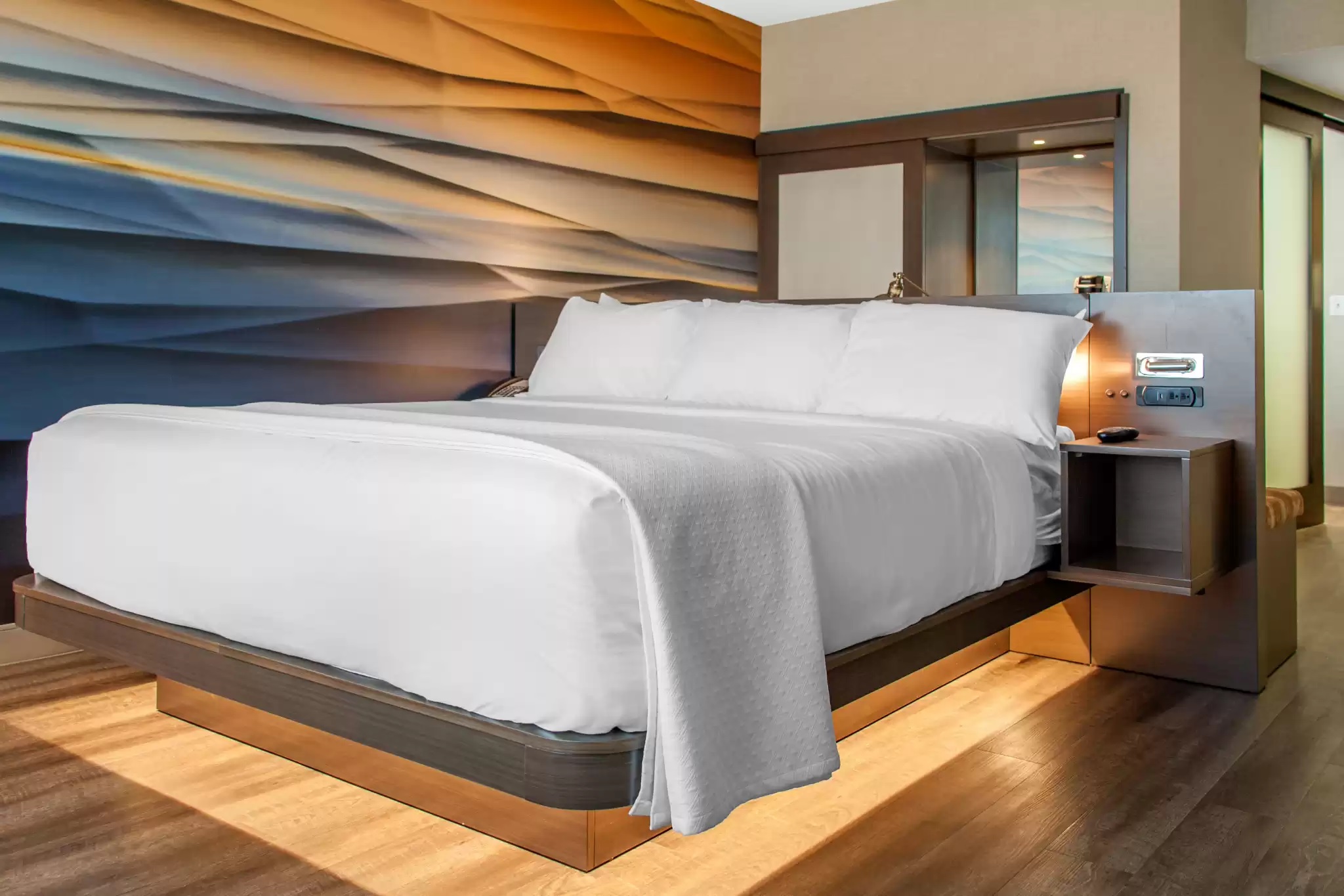 a bed with white sheets and a wood floor