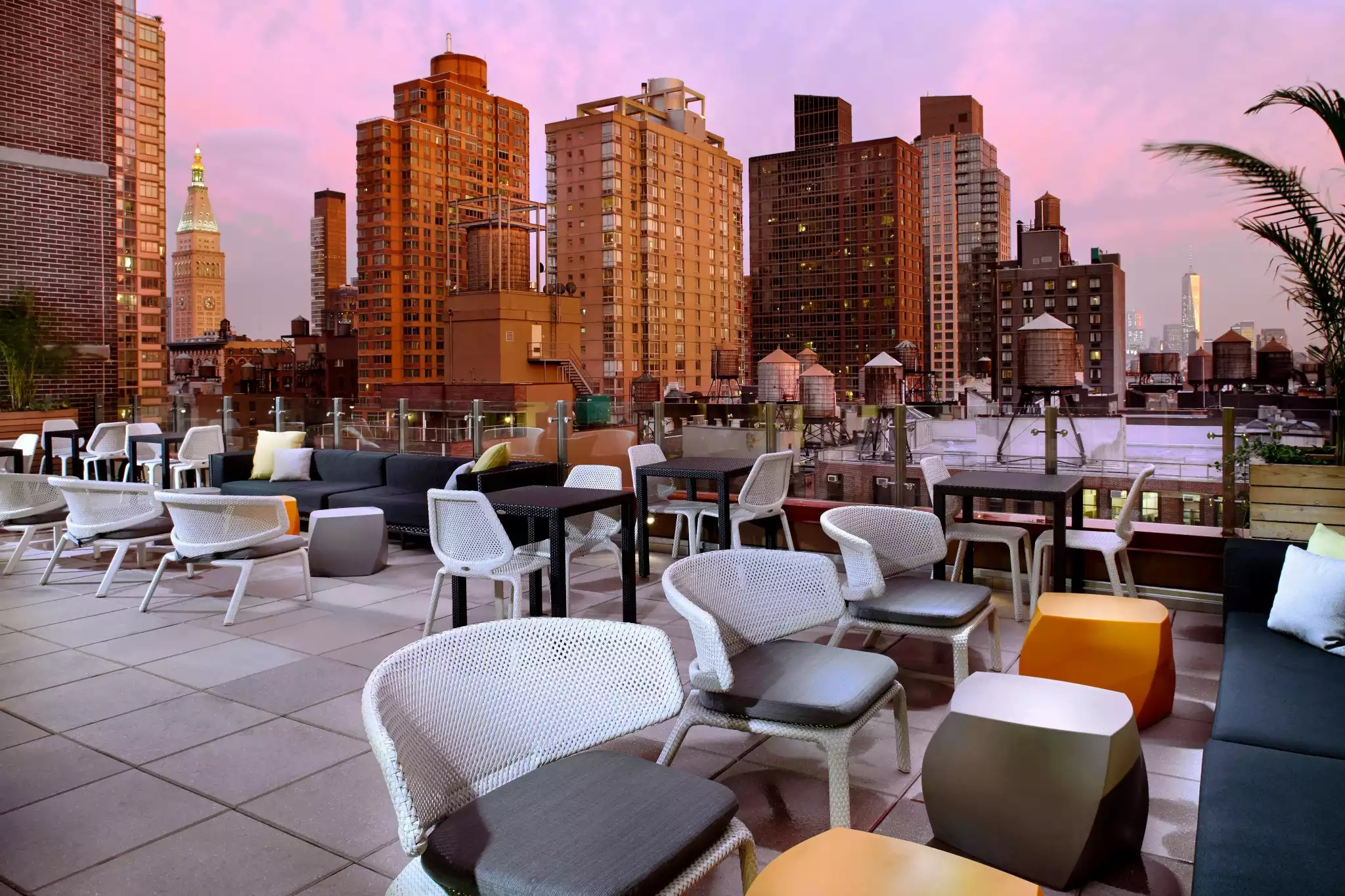 a rooftop patio with chairs and tables and a city skyline